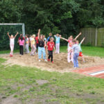 Kinder stehen im Sand der Weitsprunganlage